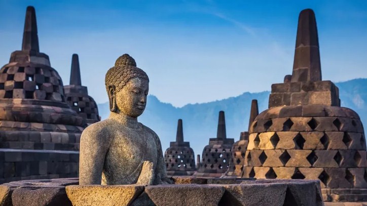 Candi Borobudur di tengah pemandangan hijau, dengan stupa-stupa Buddha terlihat jelas