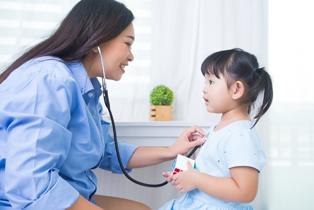 Anak sedang diperiksa oleh dokter pediatri dengan senyuman hangat di klinik modern.